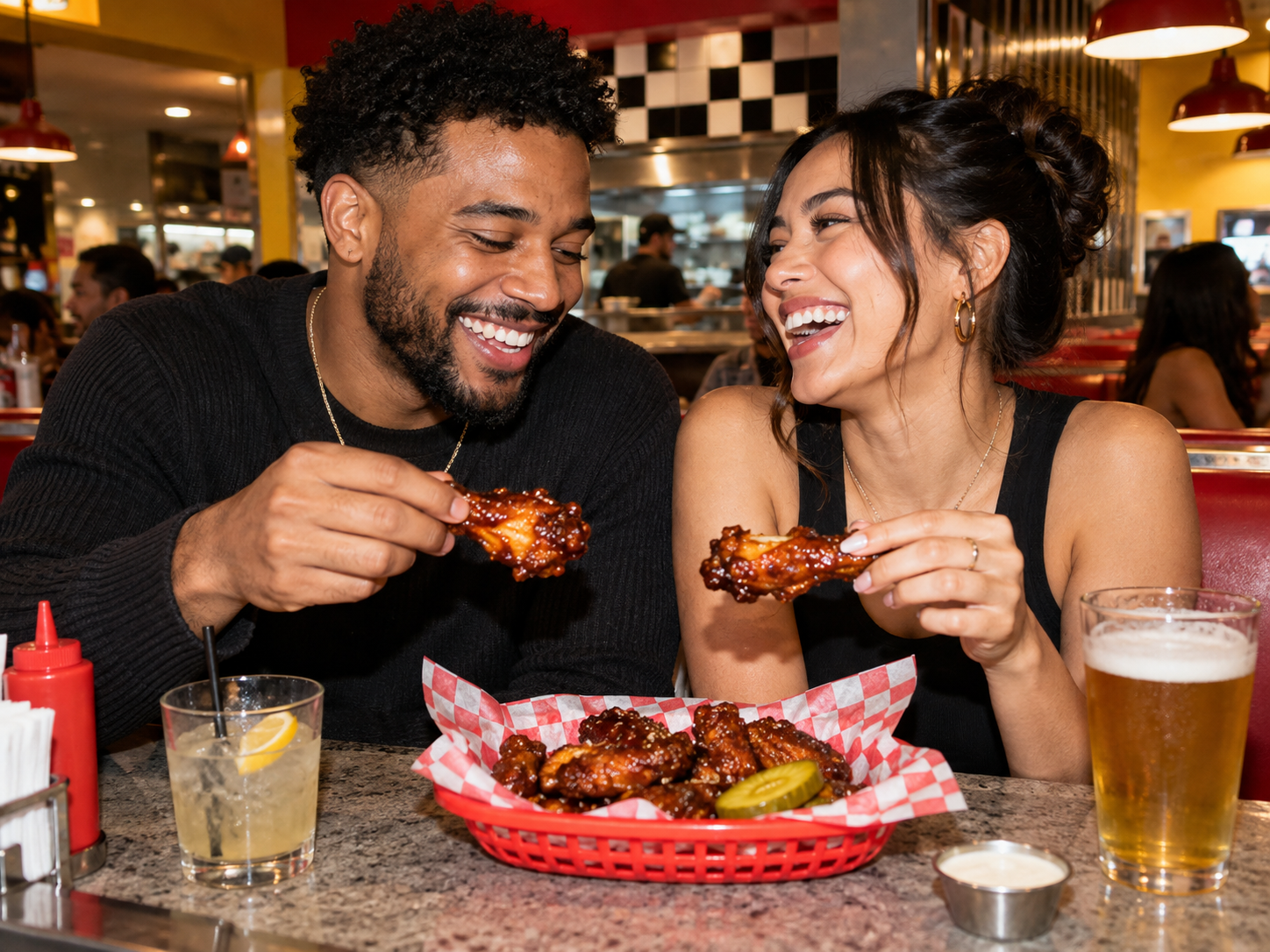 A couple laughing together over a basket of glazed chicken wings
